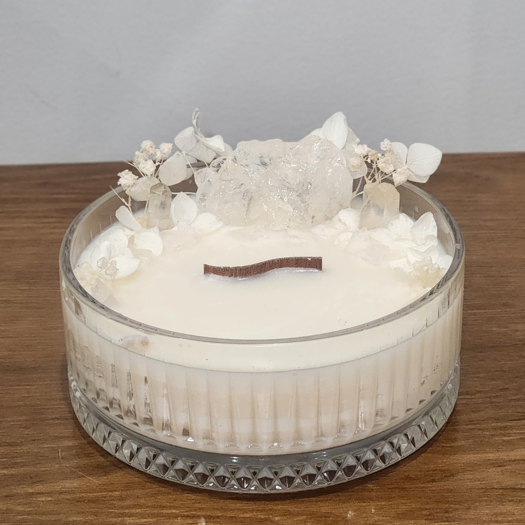 Candle in a glass container with decorative elements on a wooden surface
